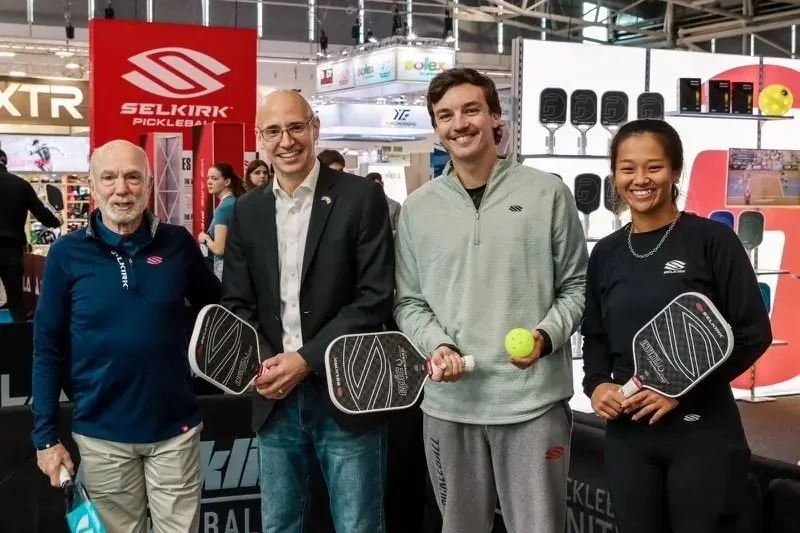 Kyle with the Selkirk team at a trade show booth holding paddles